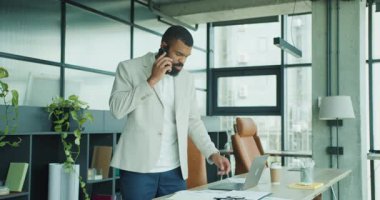 Bir adam modern bir ofis ortamında oturmuş çeşitli belgeleri incelerken önemli bir iş görüşmesi yapıyor.