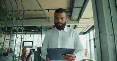 İyi aydınlatılmış, modern ofis ortamında, bir iş adamı çeşitli önemli belgeleri özenle inceler.