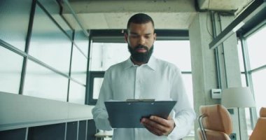 Modern ofis ortamında iş verilerini özenle inceleyen ve analiz eden kendini işine adamış bir profesyonel.