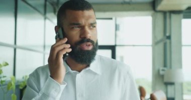 Kendini işine adamış bir profesyonel, üretkenliği arttıran şık ve modern bir ofis alanında telefon görüşmesi yapmakla meşgul.