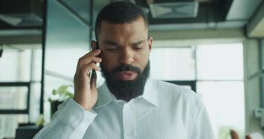 Odaklanmış bir işadamı telefonuyla çağdaş bir ofis alanında konuşuyor, profesyonelliği aktarıyor..