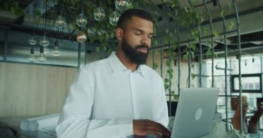 Odaklanmış bir adam, önemli çalışmalarına, yeşillik dolu şık ve modern bir ofiste yoğunlaşır.