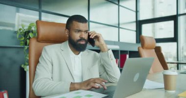 Çağdaş bir çalışma alanındaki belgeleri incelerken telefon görüşmesi yapan bir iş adamı.