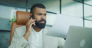 Odaklanmış bir işadamı, bilgisayarındaki evrak işlerini yönetirken aynı anda birden fazla iş yapabilir.