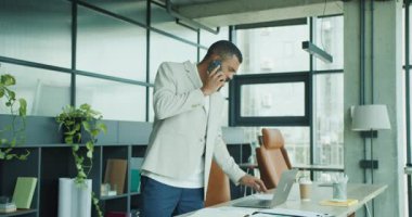 Kendini işine adamış bir işadamı modern çağdaş ofis ortamında aktif olarak bir telefon görüşmesi yapmaktadır.
