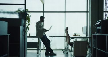 Kendini işine adamış, üretkenliği arttıran modern, doğal aydınlık bir ofiste çalışan büyüleyici bir siluet.