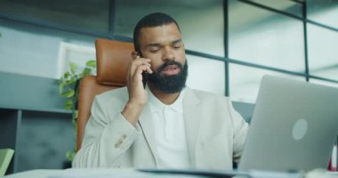 Bir iş adamı, şık bir ofiste dizüstü bilgisayarı üzerinde çalışırken çok önemli bir iş görüşmesi yapar.