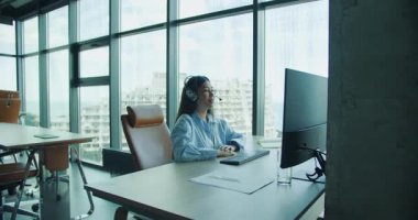 Modern ve çağdaş bir ofis alanında özenle bilgisayar kullanan son derece odaklanmış genç bir kadın. Yüksek kalite 4k görüntü