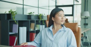 Kararlı genç bir kadın modern bir ofiste oturuyor, işini ve geleceğe dair umutlarını berraklıkla düşünüyor. Yüksek kalite 4k görüntü