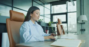 Şık bir ofis alanında dizüstü bilgisayarda yazan genç bir kadın. Konsantrasyon ve verimlilik gösteriyor. Yüksek kalite 4k görüntü