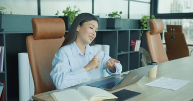 Bir iş kadını, çağdaş bir ofiste profesyonelliğini gösterirken dizüstü bilgisayarıyla etkileşime girer. Yüksek kalite 4k görüntü