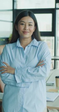 Kendine güvenen, kendine güvenen, şık profesyonel kıyafetler giyen bir kadın modern ofis ortamında gururla durur.