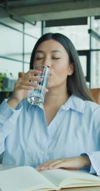 Modern bir kafede suyu yudumlarken huzurlu bir dinlenme anı, farkındalığı yakalıyor.