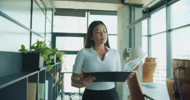 Kendini işine adamış profesyonel bir kadın zarif ve çağdaş ofis ortamında önemli belgeleri titizlikle inceler. Yüksek kalite 4k görüntü