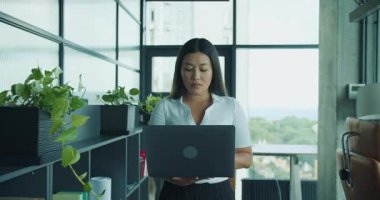 Yetenekli profesyonel bir kadın modern ve çağdaş bir ofis ortamında özenle dizüstü bilgisayarı üzerinde çalışıyor. Yüksek kalite 4k görüntü