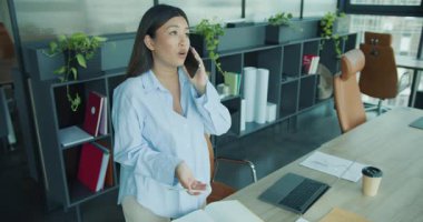 Profesyonel bir kadın şık ofisinde önemli iş belgelerini incelerken telefonla konuşuyor. Yüksek kalite 4k görüntü