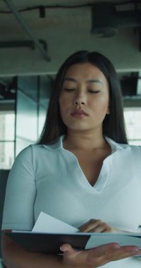 Modern bir ofiste belgeleri inceleyen odaklanmış bir kişi, konsantrasyon ve profesyonelliği gösteriyor.