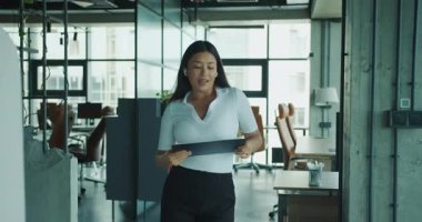 Odaklanmış bir iş kadını çalışma alanında bir tablet kullanarak modern profesyonellik ve verimliliğin örneğini veriyor. Yüksek kalite 4k görüntü