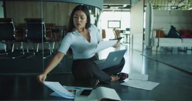 Bir kadın, modern, profesyonel bir ofisteki verimliliği vurgulamak için bilgisayarındaki belgeleri analiz eder.