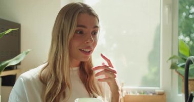 Bir kadın, aydınlık, samimi ve davetkar bir ortamda sıcak bir içkinin tadını çıkarırken gerçekten mutlu bir anı paylaşır.