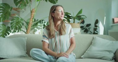 Bir kadın güzel bitkilerle dolu rahat bir oturma odasında laptopunu rahatça kullanıyor. Yüksek kalite 4k görüntü