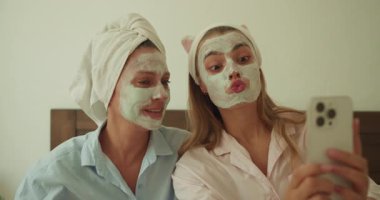 İki yakın arkadaş, eğlenceli maske oturumlarında komik suratlar yaparken keyifli bir güzellik anının tadını çıkarıyorlar.