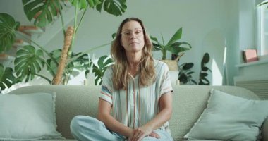 Huzurlu bir kadın, yemyeşil bitkiler ve bol miktarda doğal ışıkla dolu oturma odasında neşe bulur.