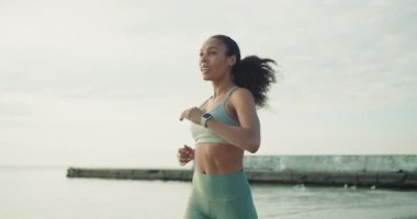 Formda ve sağlıklı bir kadın sahilde enerjik ve ferahlatıcı bir sabah koşusundan zevk alır. Sağlık ve canlılığı teşvik eder.