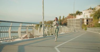 Fevkalade güzel bir günde okyanusun kenarında koşan sağlıklı ve sağlıklı bir kadın.