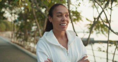 Huzurlu suyun yanında gülümseyen neşeli bir kadın doğanın nefes kesici güzelliğini ve huzurlu çevresini takdir eder.