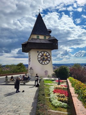 Graz, Avusturya - 22 Eylül 2022: Styria 'nın başkenti Graz' ın UNESCO dünya mirası sahasının simgesi olan Schlossberg tepesinde yer alan Uhrturm adlı saat kulesinde Styrian armonikasıyla tanınmayan turistler ve müzisyenler