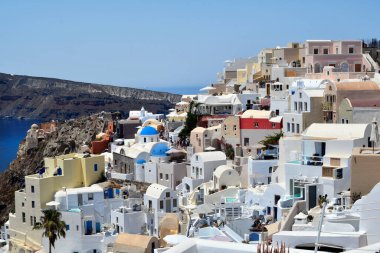 Oia, Santorini, Yunanistan - 22 Haziran 2022: Oia kasabasının dar sokaklarında turist kalabalığı, kalderaya bakan kayalıkların üzerine yuva yapmış beyaz evler inşa edilmiştir.