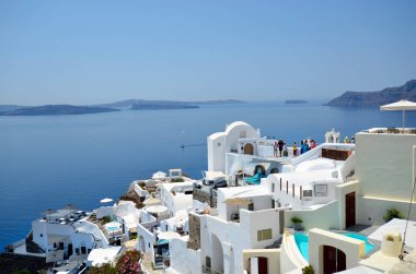 Oia, Santorini, Yunanistan - 22 Haziran 2022: Oia kentinin manzarası, yuvalanmış beyaz evler kalderaya bakan kayalıkların üzerine inşa edilmiştir.