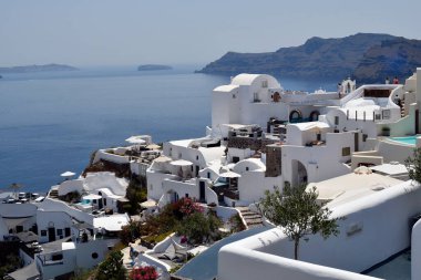Oia, Santorini, Yunanistan - 22 Haziran 2022: Oia kentinin manzarası, yuvalanmış beyaz evler kalderaya bakan kayalıkların üzerine inşa edilmiştir.