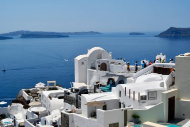 Oia, Santorini, Yunanistan - 22 Haziran 2022: Oia kasabasının manzarası, Ege Denizi 'ndeki kalderaya bakan kayalıkların üzerine yuva yapmış beyaz evler inşa edilmiştir.