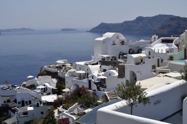 Oia, Santorini, Yunanistan - 22 Haziran 2022: Oia kentinin manzarası, yuvalanmış beyaz evler kalderaya bakan kayalıkların üzerine inşa edilmiştir.