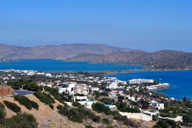 Greece, Crete, panorama from Elounda with hotel complexes on the Cretan Sea with the narrow causeway to the Spinalonga peninsula, in the background the former Venetian fortress and leper island