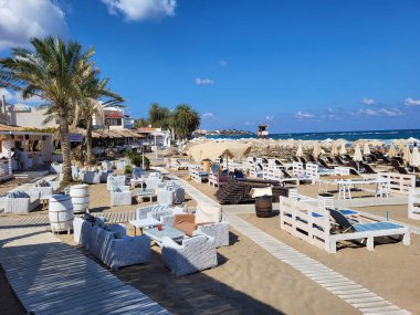 Crete, Greece - October 09, 2022: Beach with sun beds and beach restaurant in Stalida a preferred tourist location for swimming and relaxing clipart