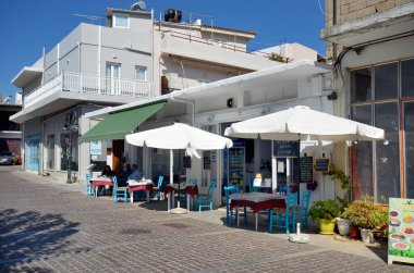 Mochos, Greece - October 11, 2022: unknown people are sitting in the outside area of a small cafe in the cobbled main street