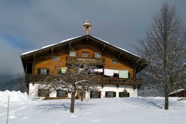 Austria, Tyrol,  house of traditional construction with a bell tower in a wintry setting, laundry drying on the balcony