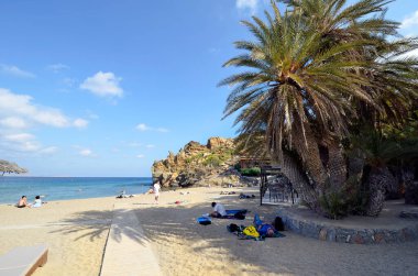 Vai, Yunanistan - 12 Ekim 2022: Adanın en kuzeydoğusunda kumlu plajları olan pek çok palmiye ağacı nedeniyle, Vai plajında dinlenen kimliği belirsiz insanlar popüler fakat korunması zor bir bölge