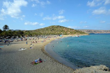 Vai, Yunanistan - 12 Ekim 2022: Adanın en kuzeydoğusunda kumlu plajları olan pek çok palmiye ağacı nedeniyle, Vai plajında dinlenen kimliği belirsiz insanlar popüler fakat korunması zor bir bölge