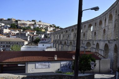 Kavala, Yunanistan - 13 Haziran 2023: Bizans 16. yüzyıldan kalma su kemeri Kamares ve tepede güçlendirilmiş duvarlı ortaçağ kalesi, Ege Denizi üzerindeki kentin simgeleri