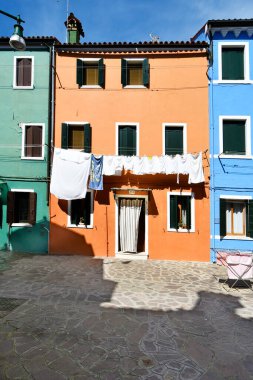 Burano, İtalya - 17 Nisan 2024: Venedik Gölündeki adanın renkli evleri, kuruması için yeni yıkanmış çamaşırlar