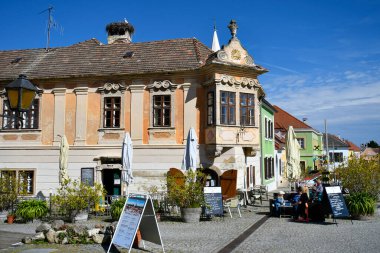 Rust, Austria - March 23, 2024: Unknown people relax on a warm spring day in a restaurant decorated with reliefs at the Town Hall Square in the so-called stork town on Lake Neusiedl with its picturesque houses, UNESCO World Heritage Site in Burgenlan clipart