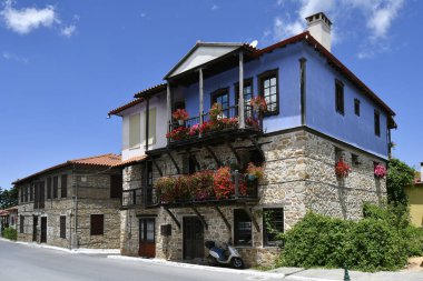 Arnea, Yunanistan - 15 Haziran 2024: Halkidiki dağlarındaki pitoresk köyde balkonda çiçekli güzel renkli evler