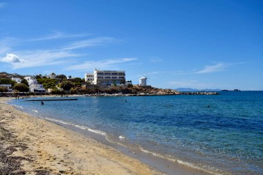 Paros, Yunanistan - 17 Eylül 2024: Parakia sahilinde küçük bir balıkçılık limanı ve yel değirmeniyle tanınmayan kişiler, bir tanesi kafe olarak kullanılıyor