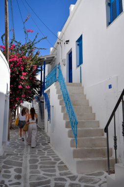 Paros, Yunanistan - 17 Eylül 2024: Parikia 'nın eski ve güzel çiçek açan Baugainvillea kentindeki resimli dar sokaklarda bilinmeyen insanlar geziniyor