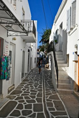 Parikia, Yunanistan - 17 Eylül 2024: Parikia 'da çeşitli dükkanlarla birlikte bilinmeyen kişiler dar sokaklarda yürüyor
