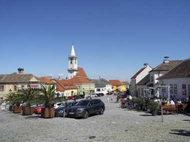 Pas, Avusturya - 20 Nisan 2025: Bilinmeyen ziyaretçiler, UNESCO 'nun erken dönem Barok Katolik kilisesi olan kentindeki kaldırımlı kasaba meydanının etrafındaki çatılarda bulunan meyhanelerde ve leylek yuvalarında oturuyorlar